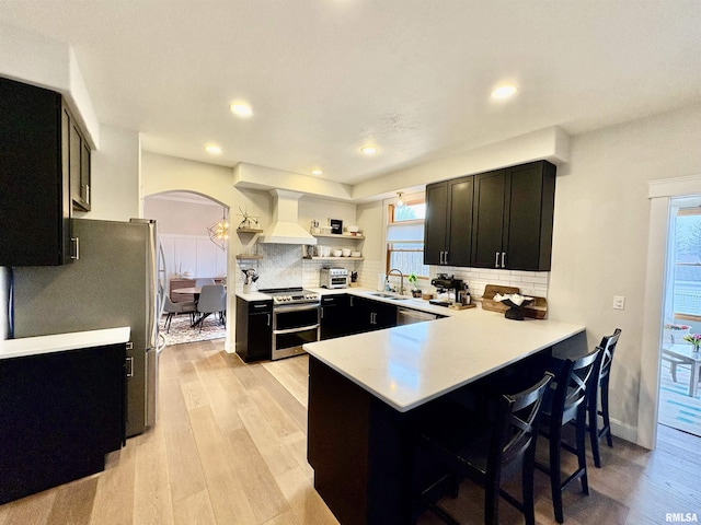 3096 Whitehaven Cir, Galesburg, IL 61401 - kitchen with stainless steel appliances, dark cabinets, a sink, premium range hood, and a peninsula