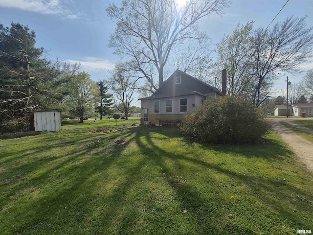view of yard featuring an outdoor structure, a storage unit, and driveway