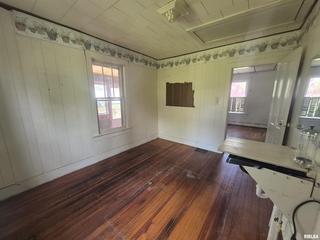 empty room with a baseboard heating unit, visible vents, and dark wood finished floors