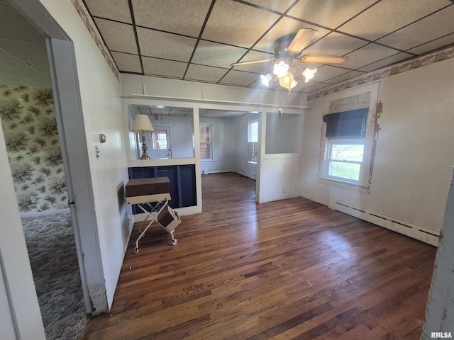 empty room featuring a baseboard radiator, baseboards, dark wood-type flooring, and ceiling fan