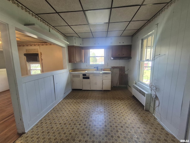 kitchen featuring a sink, light floors, light countertops, radiator, and a paneled ceiling