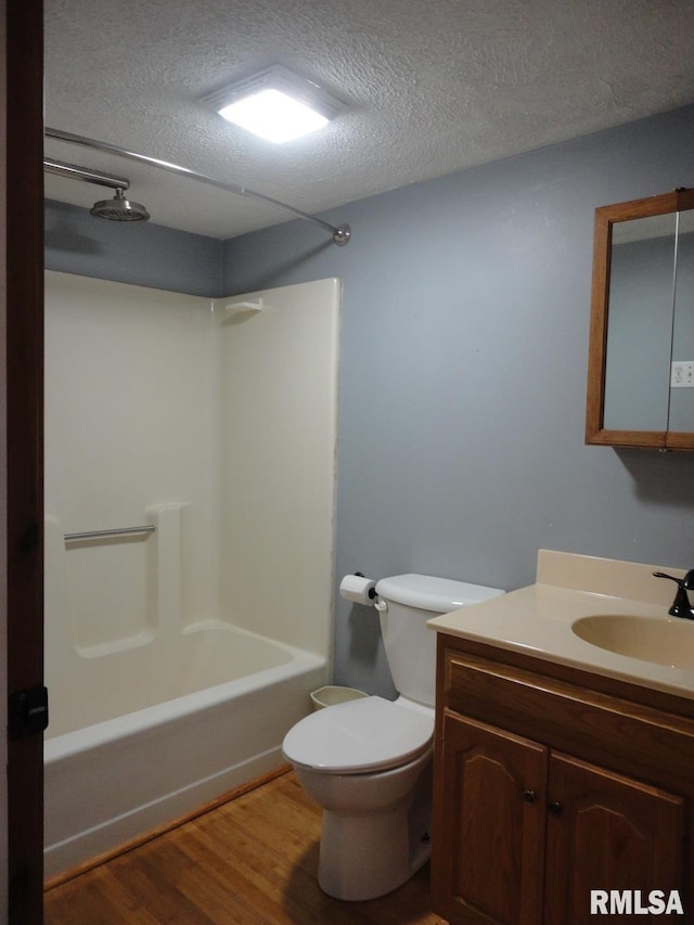 full bath featuring washtub / shower combination, wood finished floors, toilet, vanity, and a textured ceiling
