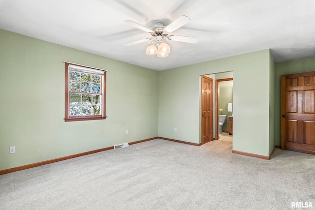unfurnished bedroom with baseboards, visible vents, light colored carpet, ceiling fan, and ensuite bath