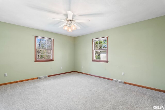 empty room featuring a wealth of natural light, baseboards, and visible vents