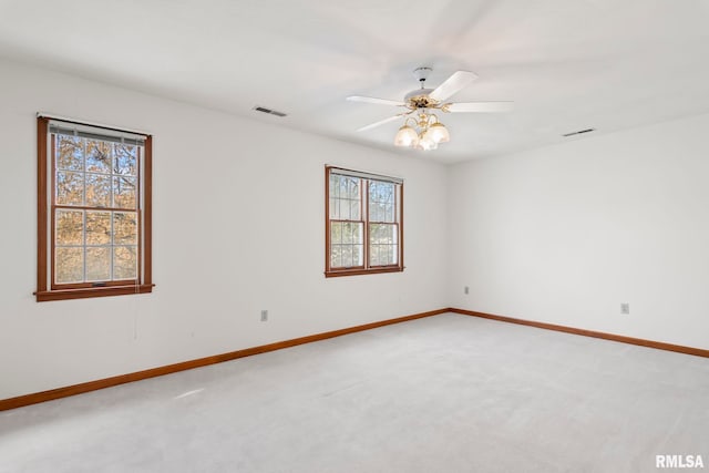 empty room with visible vents, a ceiling fan, baseboards, and light carpet