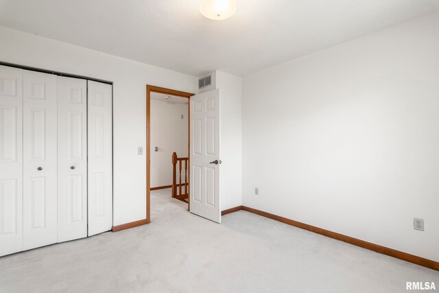 unfurnished bedroom with baseboards, light carpet, visible vents, and a closet