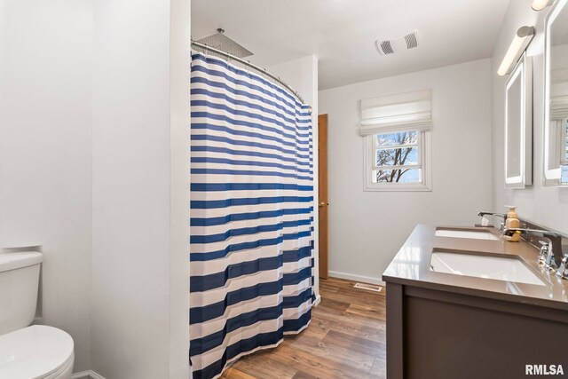 bathroom with toilet, wood finished floors, a sink, and visible vents