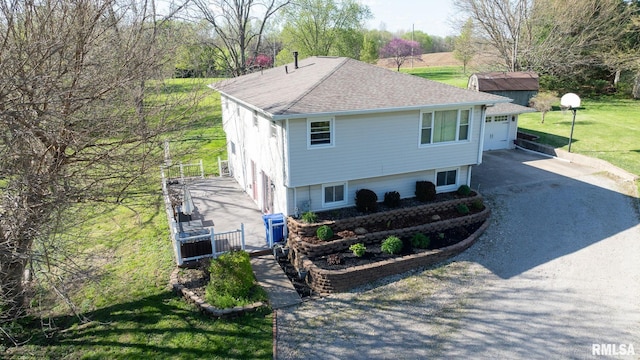 view of property exterior featuring driveway, a yard, and a shingled roof