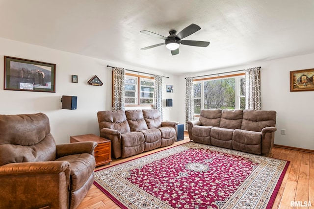 living room featuring light wood-type flooring, plenty of natural light, and a ceiling fan