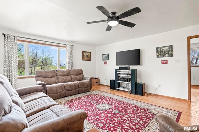 living area with baseboards, plenty of natural light, ceiling fan, and wood finished floors