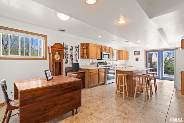 kitchen with white appliances, open shelves, light countertops, a kitchen island, and a breakfast bar area