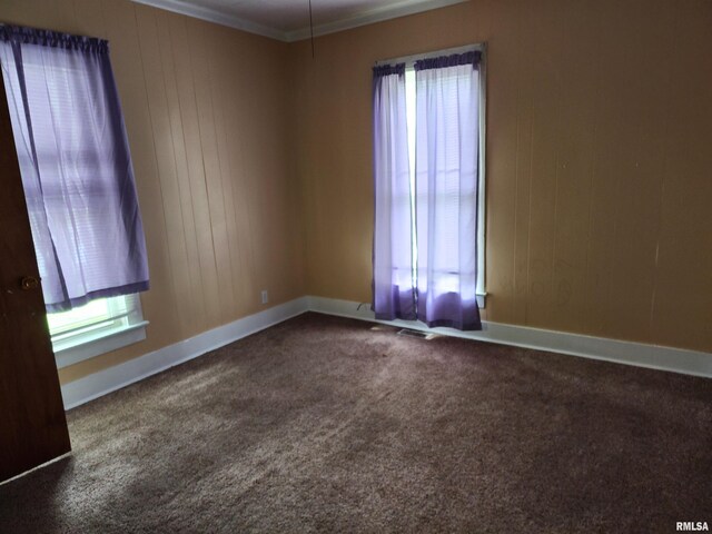 403 S Elm St, Lincoln, IL 62656 - empty room featuring dark carpet, crown molding, and wooden walls