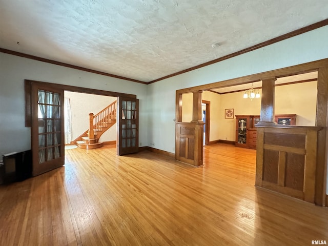 323 E Cortland St, Avon, IL 61415 - unfurnished room with stairway, light wood finished floors, an inviting chandelier, ornamental molding, and baseboards
