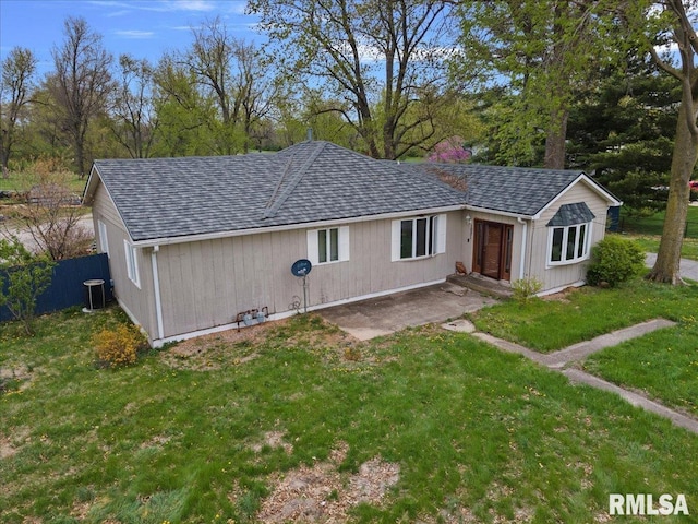 rear view of house featuring fence, a lawn, and a shingled roof