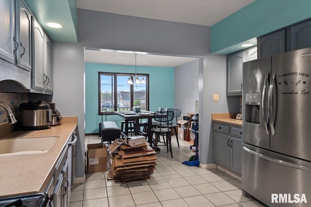 kitchen featuring stainless steel refrigerator with ice dispenser, gray cabinetry, a sink, and light tile patterned floors