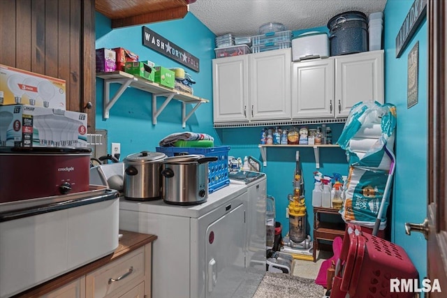 clothes washing area featuring washer and dryer, a textured ceiling, and cabinet space