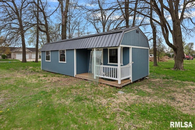 view of front of home with a gambrel roof, a front lawn, an outbuilding, and metal roof