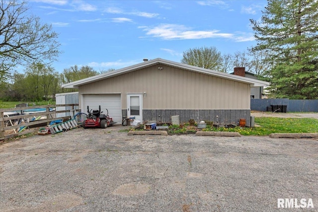 view of home's exterior with a chimney, fence, an outbuilding, and a garage