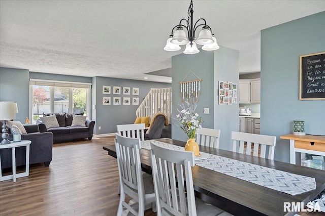 dining area with baseboards, wood finished floors, a textured ceiling, and a notable chandelier