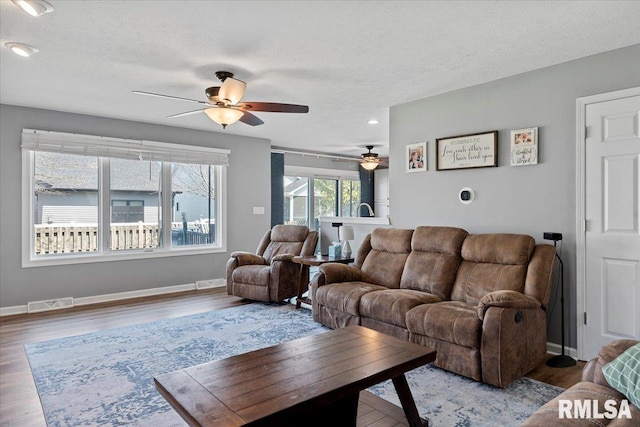 living room with ceiling fan, baseboards, wood finished floors, and a textured ceiling