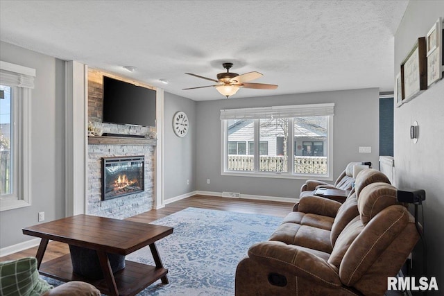 living room with baseboards, ceiling fan, and a healthy amount of sunlight
