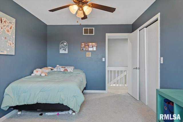 carpeted bedroom with ceiling fan, baseboards, visible vents, and a closet