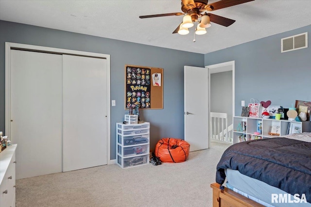 carpeted bedroom with a closet, visible vents, and a ceiling fan