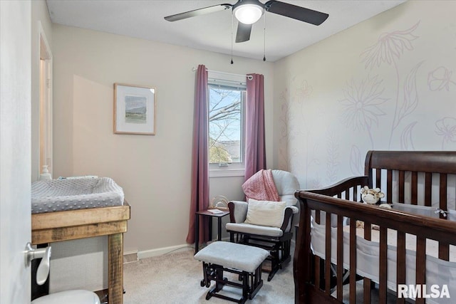 carpeted bedroom featuring a nursery area, baseboards, and ceiling fan