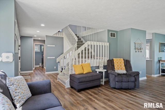 living area with baseboards, wood finished floors, recessed lighting, and stairway
