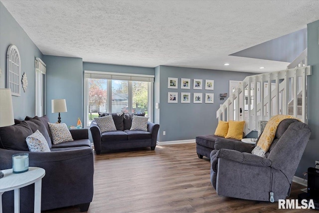 living room featuring baseboards, dark wood-style floors, a textured ceiling, and stairs