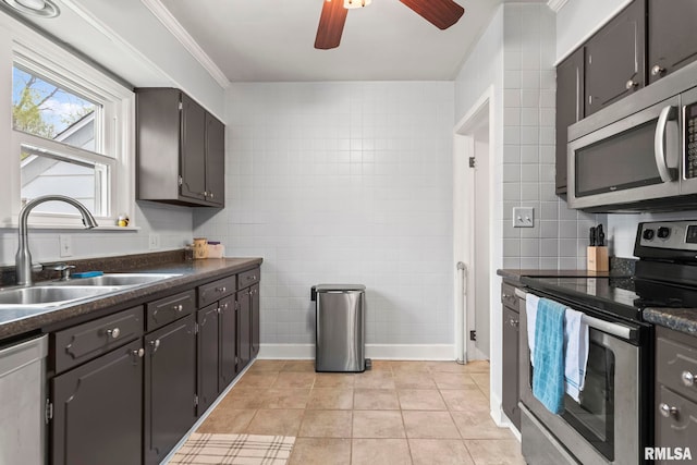 kitchen with a ceiling fan, dark countertops, a sink, light tile patterned flooring, and appliances with stainless steel finishes