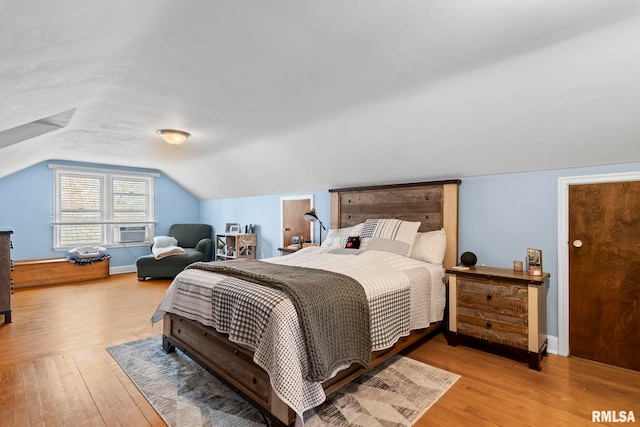 bedroom with baseboards, vaulted ceiling, hardwood / wood-style floors, and cooling unit