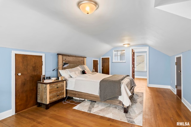 bedroom with lofted ceiling, baseboards, and wood-type flooring