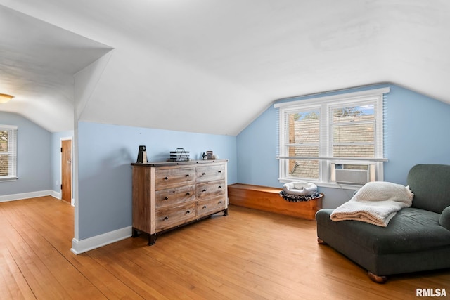 living area with baseboards, vaulted ceiling, light wood finished floors, and cooling unit