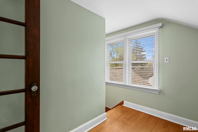 interior space with baseboards, lofted ceiling, and light wood-style flooring