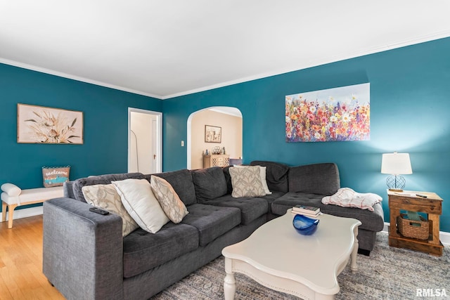 living room featuring arched walkways, ornamental molding, wood finished floors, and baseboards