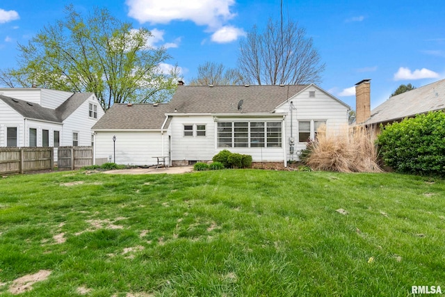 back of property with a lawn, fence, roof with shingles, and a patio