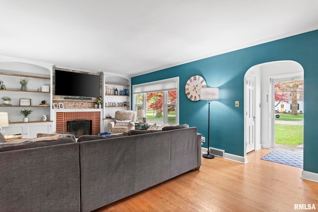 living room featuring baseboards, visible vents, a fireplace, and light wood-style floors