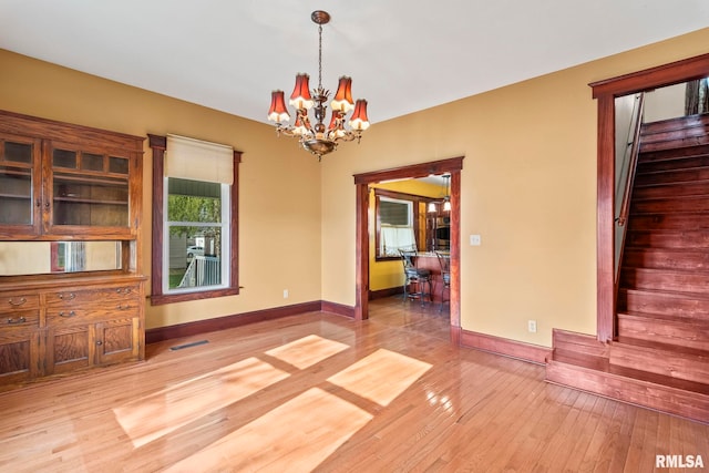 101 E Lester St, Williamsville, IL 62693 - unfurnished dining area featuring light wood-type flooring, baseboards, a chandelier, and stairs