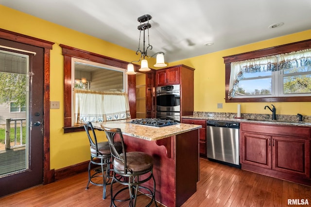 101 E Lester St, Williamsville, IL 62693 - kitchen featuring light stone counters, a sink, reddish brown cabinets, stainless steel appliances, and dark wood-style floors