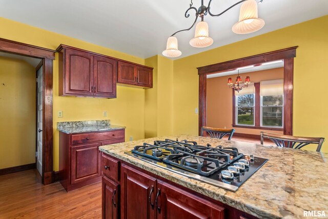 101 E Lester St, Williamsville, IL 62693 - kitchen featuring reddish brown cabinets, decorative light fixtures, a chandelier, light wood-style flooring, and black gas stovetop
