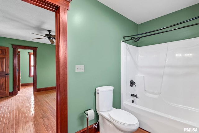 101 E Lester St, Williamsville, IL 62693 - bathroom featuring bathing tub / shower combination, toilet, a ceiling fan, wood-type flooring, and baseboards
