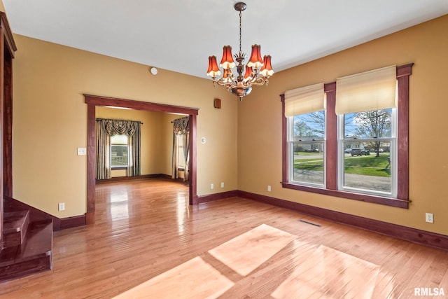 101 E Lester St, Williamsville, IL 62693 - spare room featuring baseboards, an inviting chandelier, visible vents, and light wood-style flooring