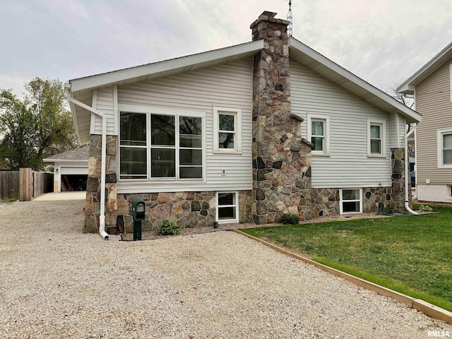 rear view of house with driveway, a chimney, fence, a garage, and a yard
