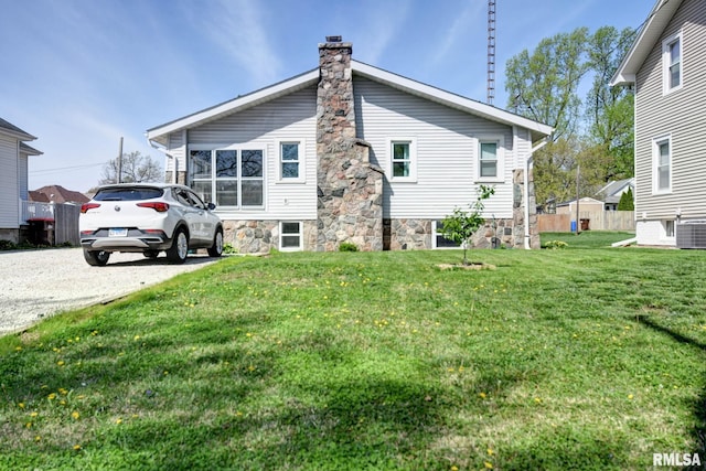 rear view of property featuring a chimney, a yard, and central AC