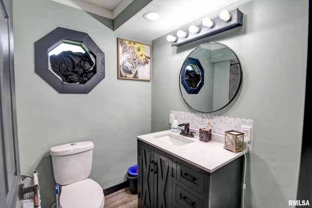 half bath featuring decorative backsplash, toilet, vanity, and wood finished floors