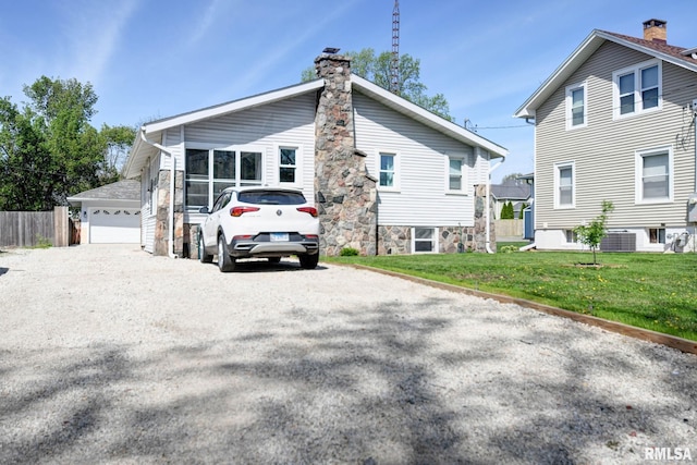 exterior space with a chimney, fence, a yard, central air condition unit, and a garage