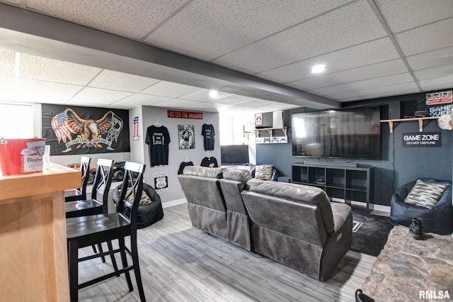 living area with wood finished floors, baseboards, and a drop ceiling