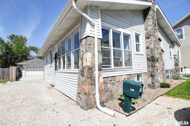 view of home's exterior featuring fence, an outdoor structure, and a detached garage