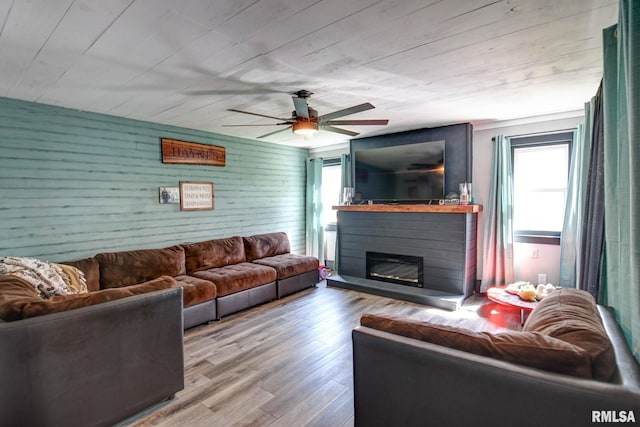living room with ceiling fan, a glass covered fireplace, and wood finished floors
